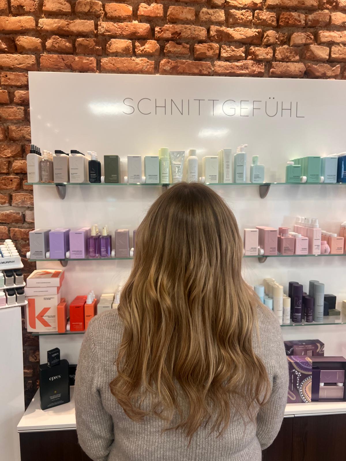 Langes Haar mit weichen Wellen vor unserer Produktwand, Ergebnis aus unserem Salon